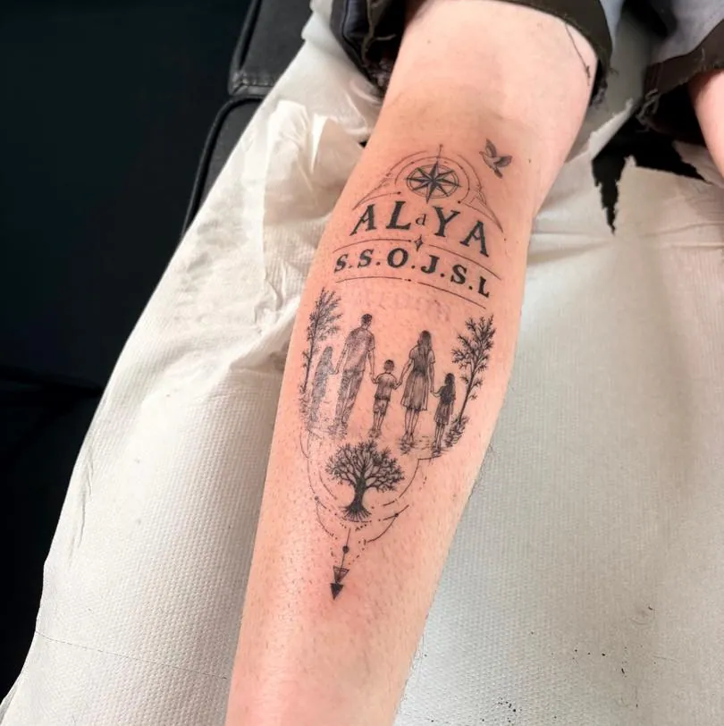 Avant-bras tatoué d'une famille qui marche main dans la main, sous une boussole et le prénom Alaya, avec un arbre en dessous.