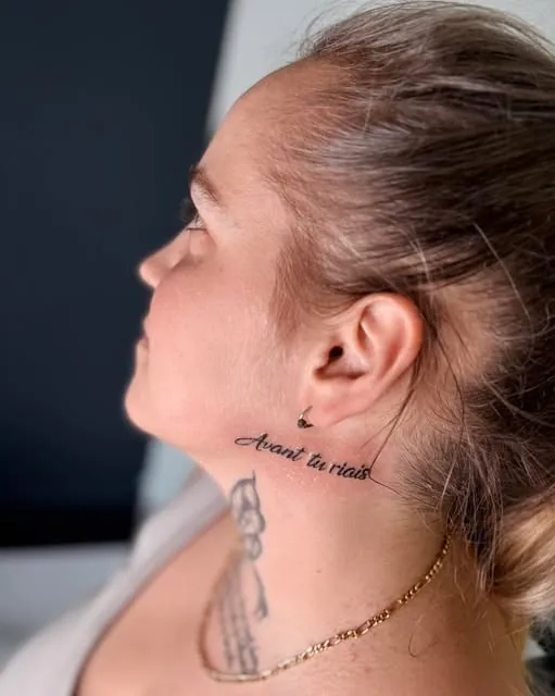 Lettrage fin «&nbsp;Avant tu riais&nbsp;» tatoué dans le cou, sous l'oreille.