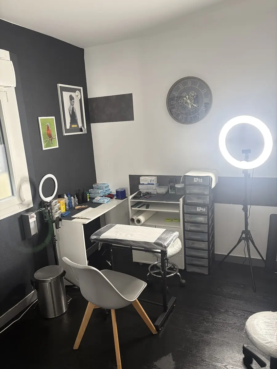 L'espace de pratique du studio, mur anthracite, lampes annulaires, poste de travail et fauteuil.